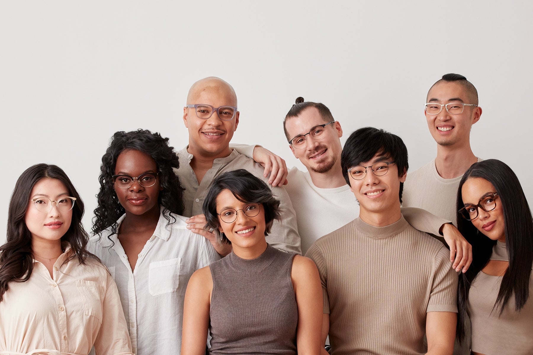 Seven people standing together against a plain wall, every one of them wearing a pair of Covry glasses.